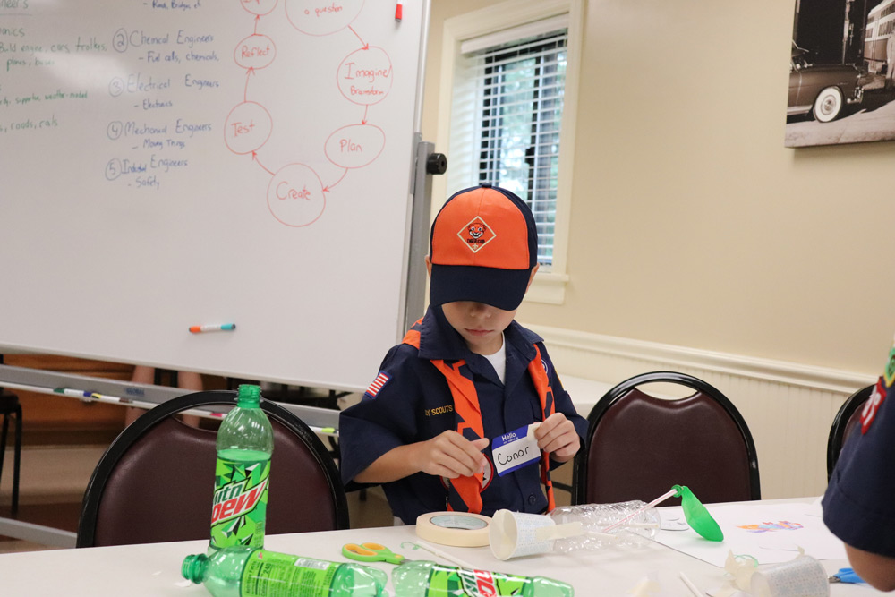 A Cub Scout uses recycled materials to design a car.