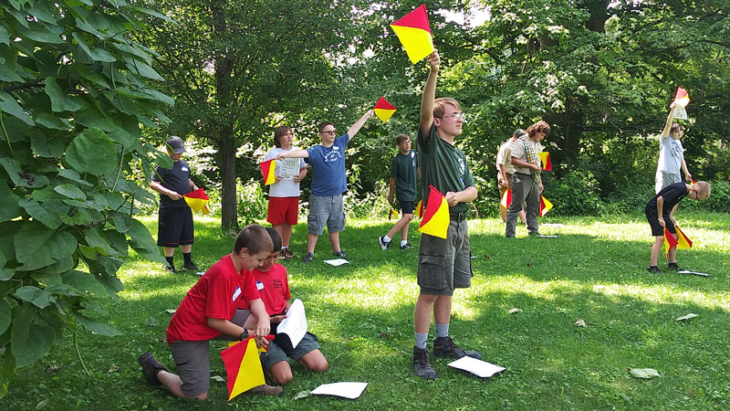 Scouts learn how to use semaphore flags during a Signs, Signals, and Codes merit badge workshop.