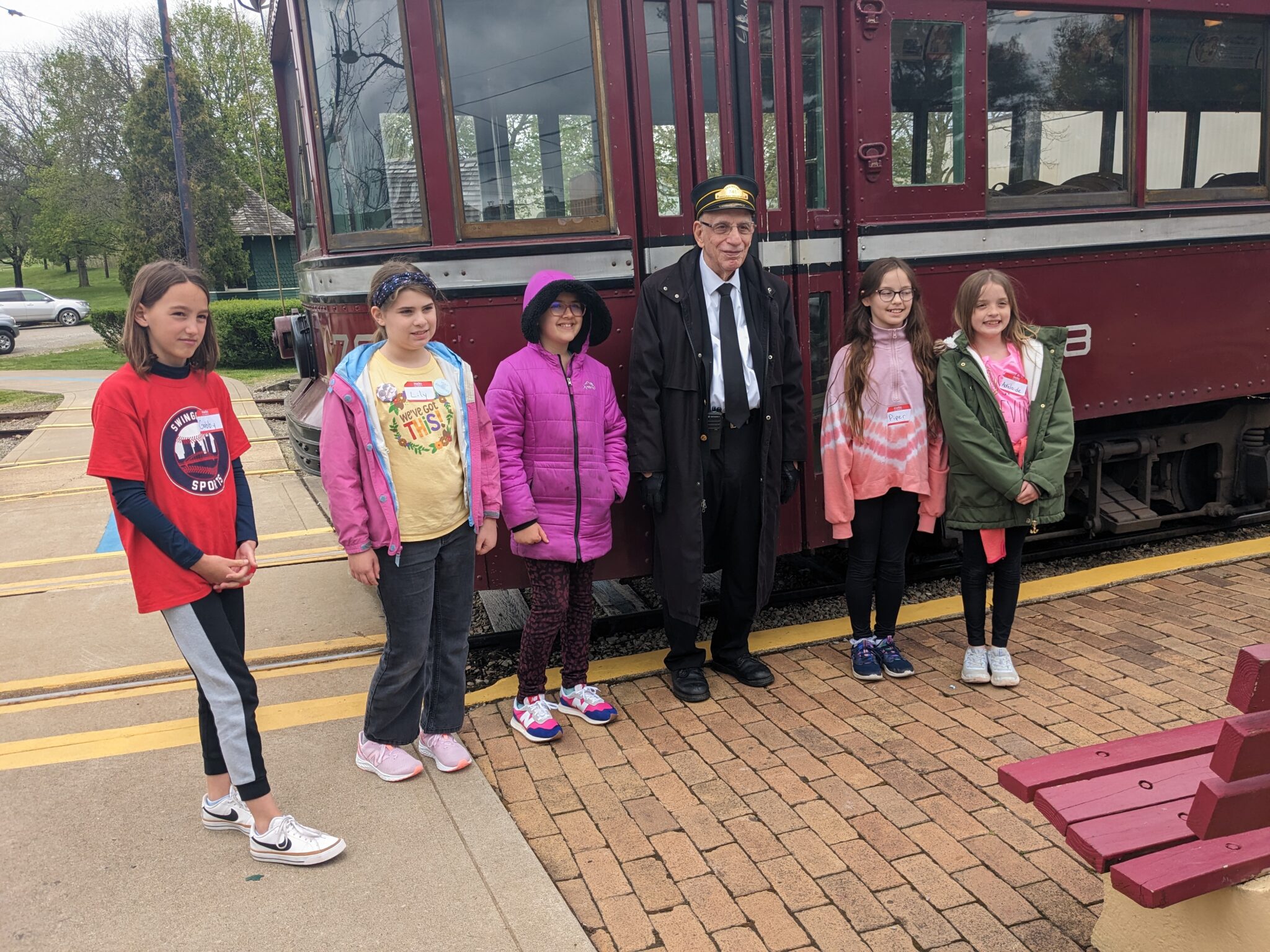 A group of girl scouts take a picture with their operator and trolley.