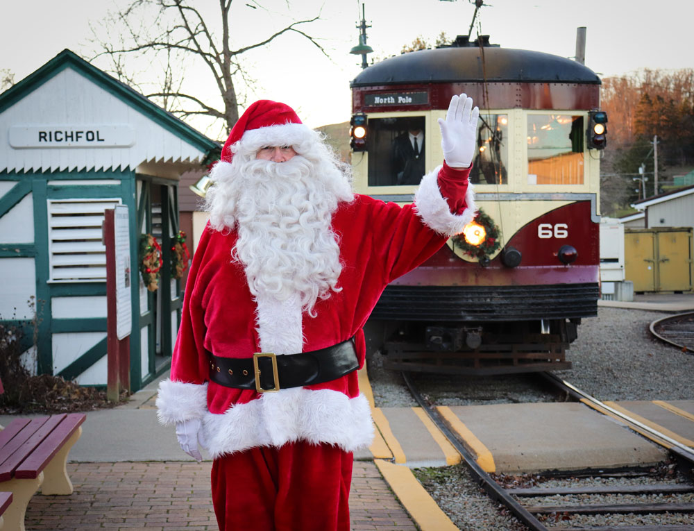 Santa waving as a red trolley (Red Arrow 66) pulls into the station (Richfol) behind him.