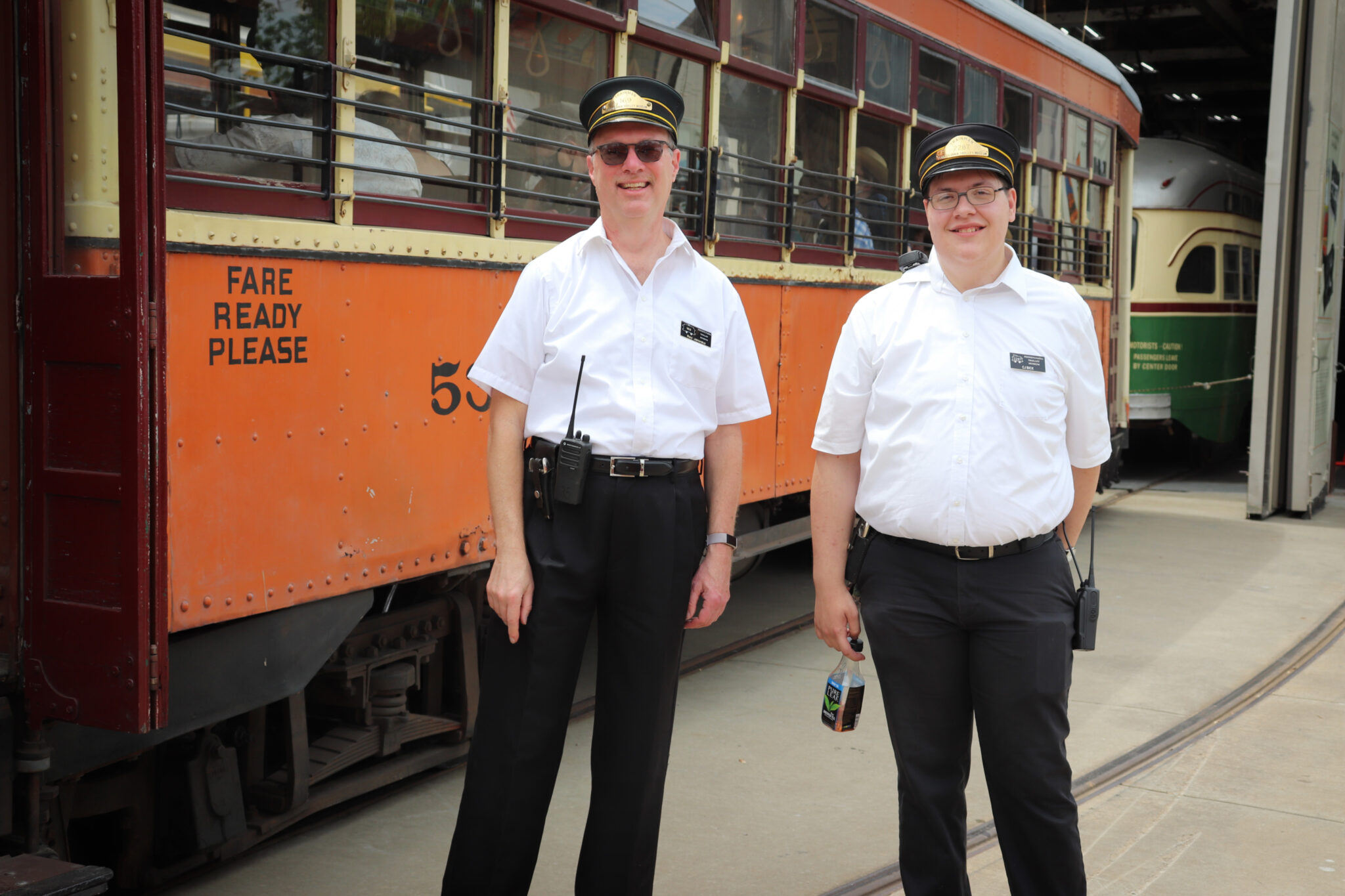 Two operators in uniform smile in front of car 5326