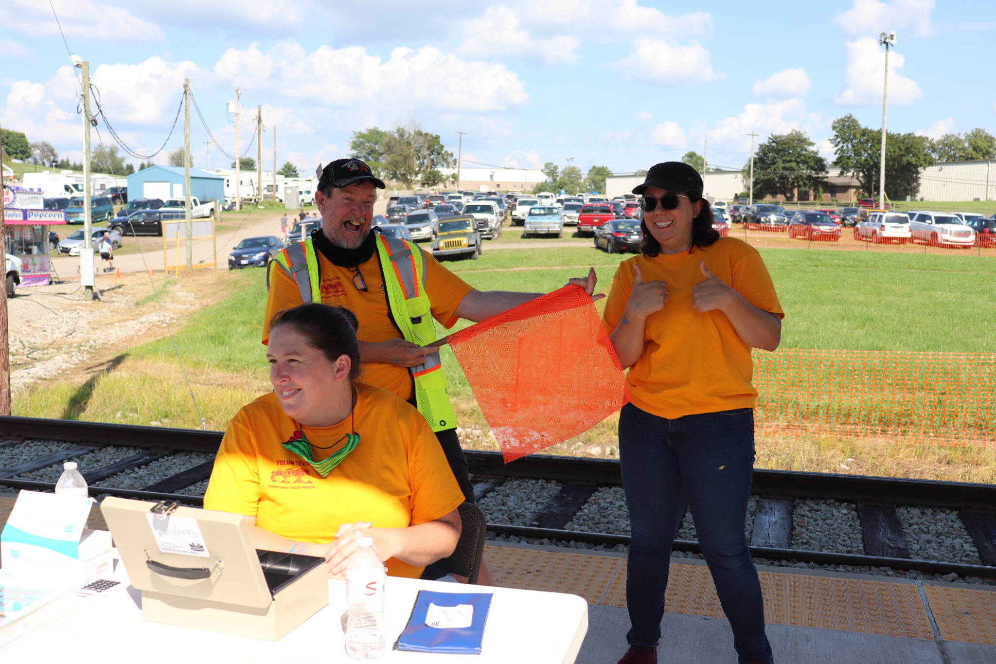 three volunteers in yellow selling tickets at county fair