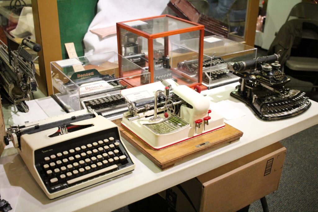 4 antique typewriters sit displayed on a table