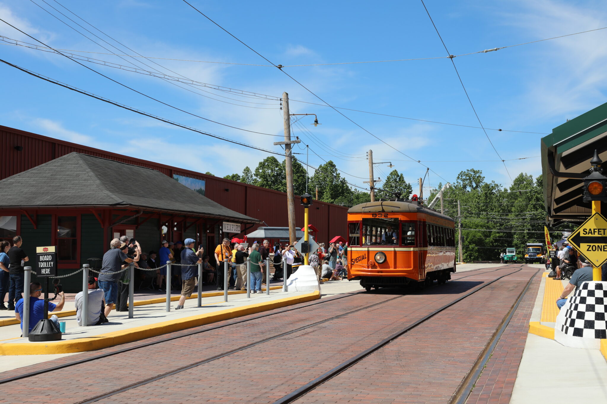 West Penn 832 comes down brick paved street with pedestrians lining street taking photos during trolley parade